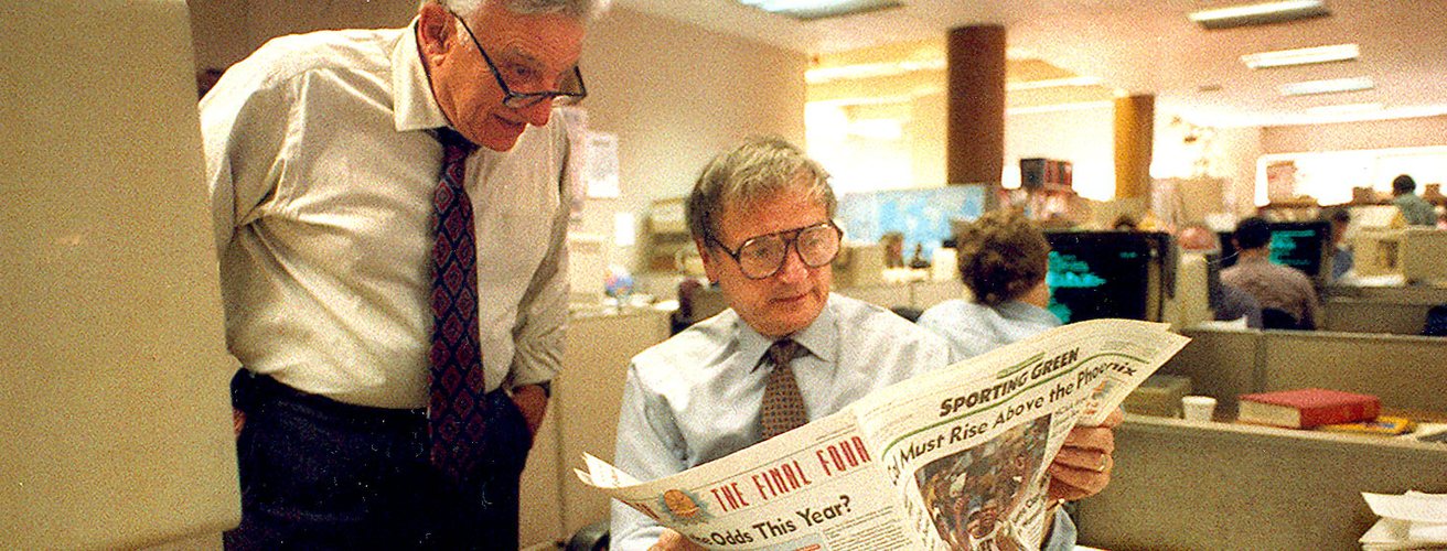 Two editors reading the sports pages in a newspaper newsroom